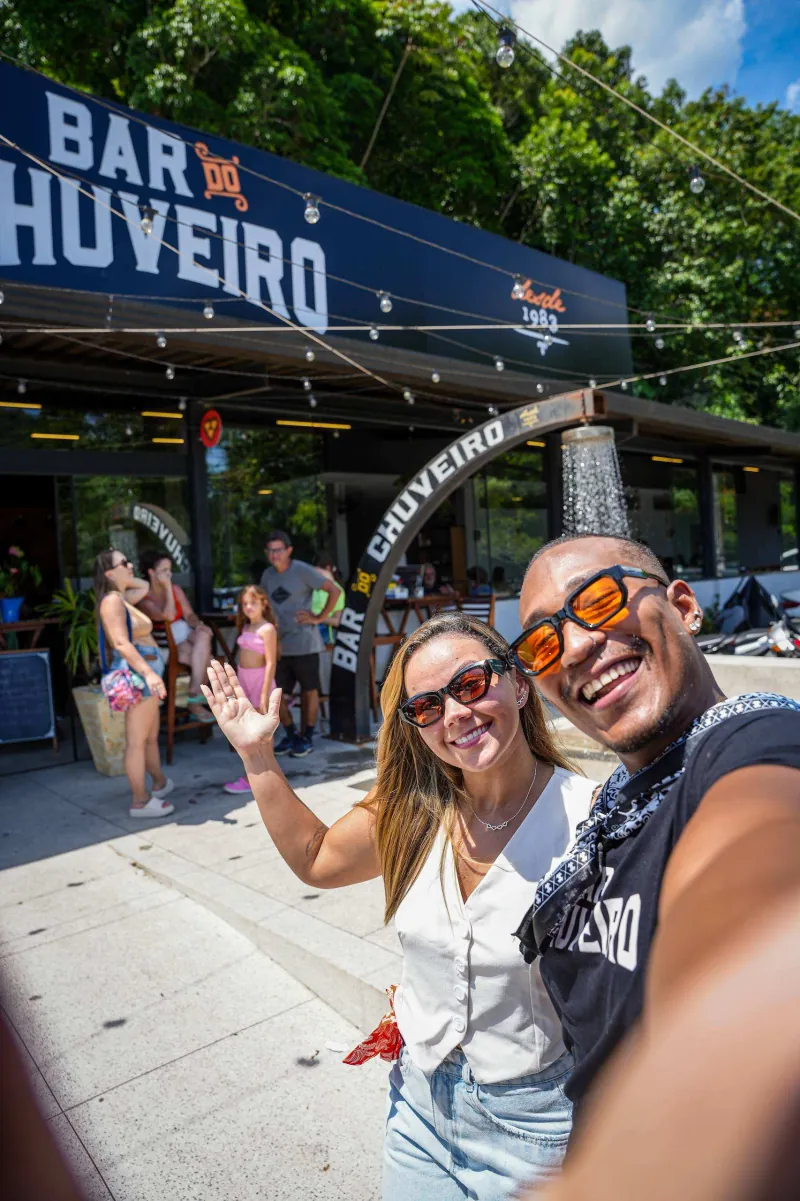Casal faz selfie sob o arco do chuveiro, na entrada da unidade Bracuí