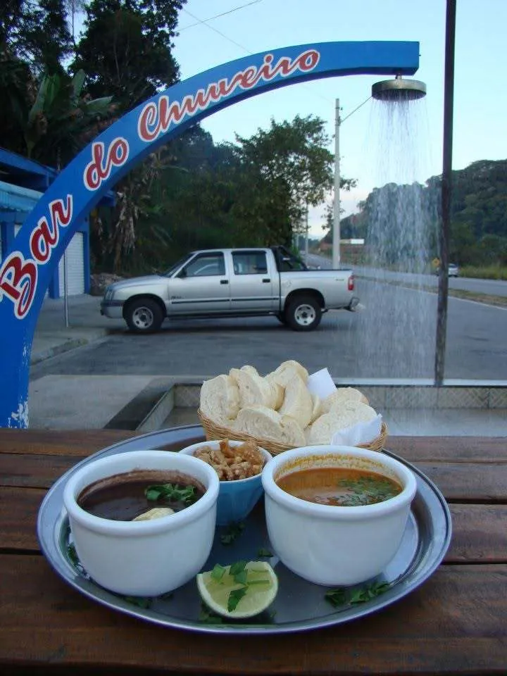 Caldos e torradas diante do antigo arco azul do chuveiro, com a Rio-Santos ao fundo