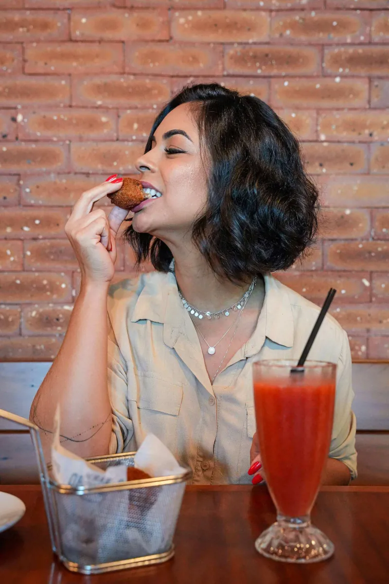 Cliente dá a primeira mordida no pastel, com um drink ao lado